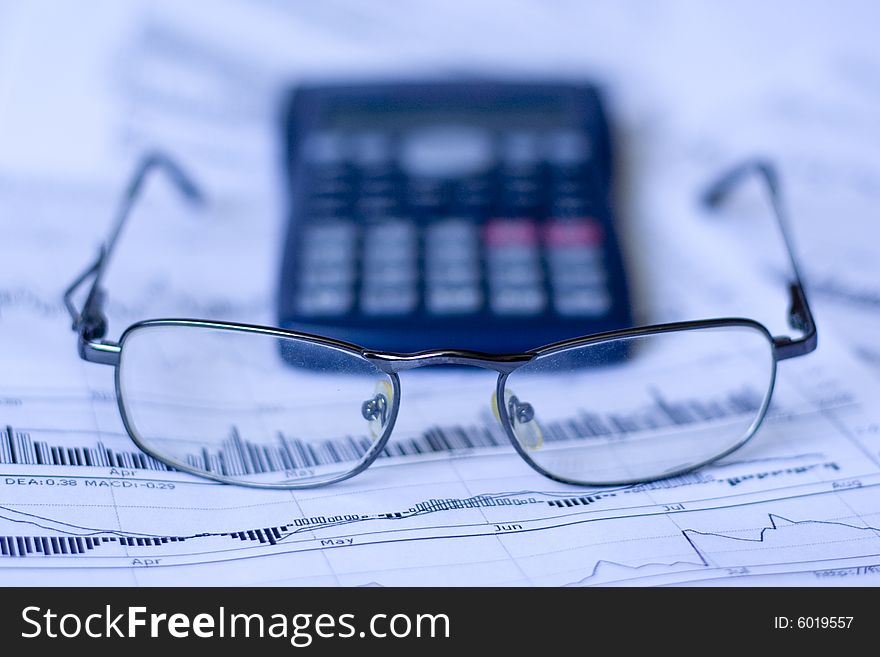 Glasses and calculator on a financial chart. Glasses and calculator on a financial chart