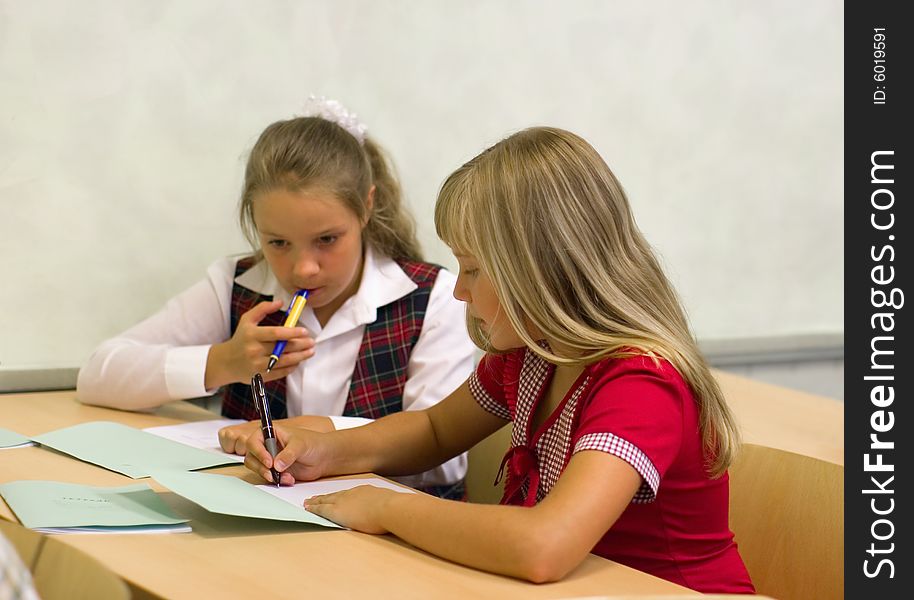 Schoolgirls talk at lesson at school. Schoolgirls talk at lesson at school.