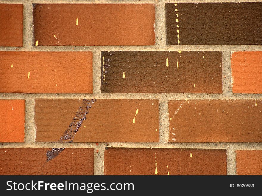 Detail of a red brick wall with some painted vandalism. Detail of a red brick wall with some painted vandalism