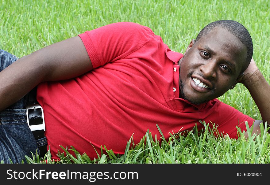 Young black man laying on green grass. Young black man laying on green grass.