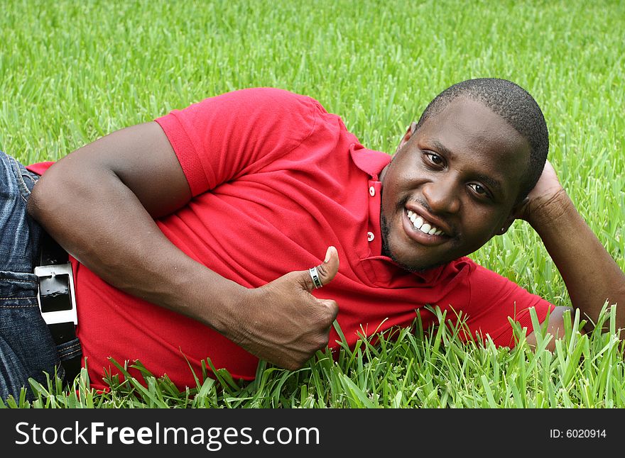 Man laying on the grass smiling and showing a thumbs up gesture. Man laying on the grass smiling and showing a thumbs up gesture.