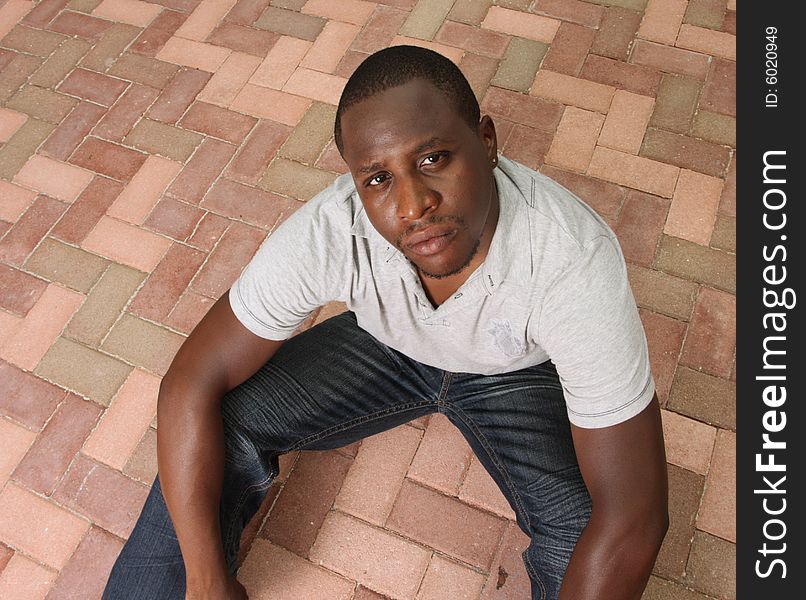 Man sitting on the ground and looking up at the camera. Man sitting on the ground and looking up at the camera.