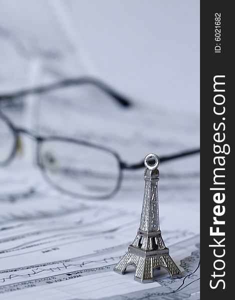 Eiffel tower on a chart. Glasses seen in the background. Shallow depth of field. Eiffel tower on a chart. Glasses seen in the background. Shallow depth of field.