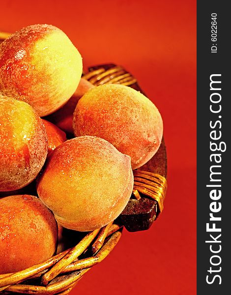 Pile of red juicy peaches on a fruit basket isolated on a red background. Pile of red juicy peaches on a fruit basket isolated on a red background.