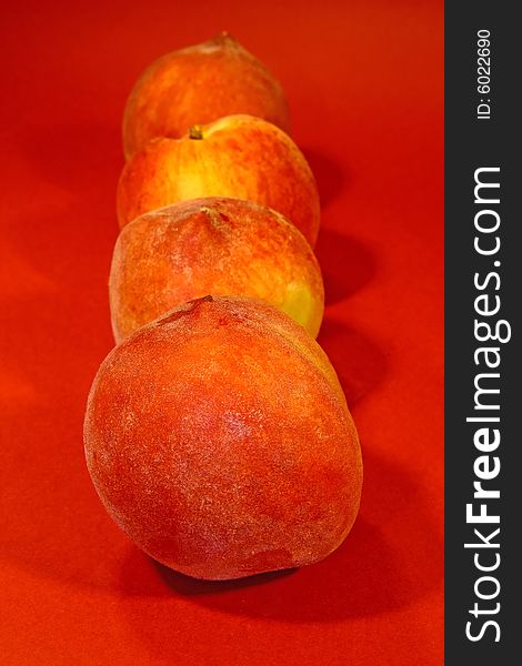 Row of juicy peaches isolated on a red background. Row of juicy peaches isolated on a red background.