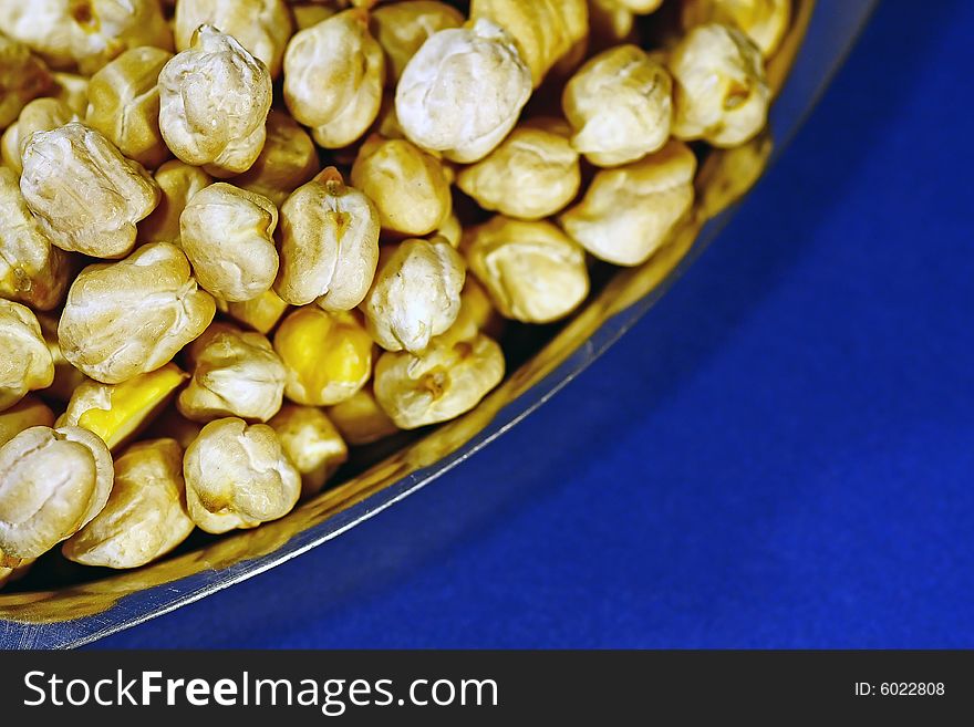 Bunch of chickpeas piled on a plate isolated on a blue background. Bunch of chickpeas piled on a plate isolated on a blue background.