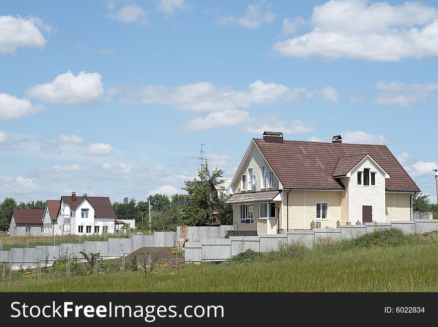 New houses surrounded with a green grass against the blue sky with clouds