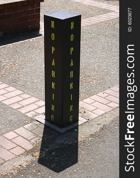 A No Parking sign painted on a steel pillar.