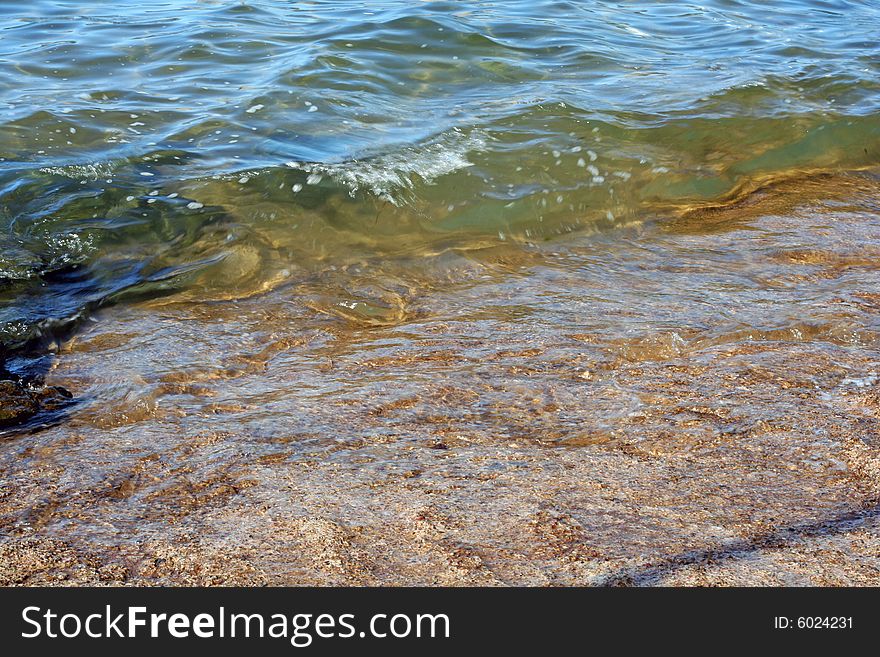 Clear green ocean water gently covers a big, flat rock. Clear green ocean water gently covers a big, flat rock.