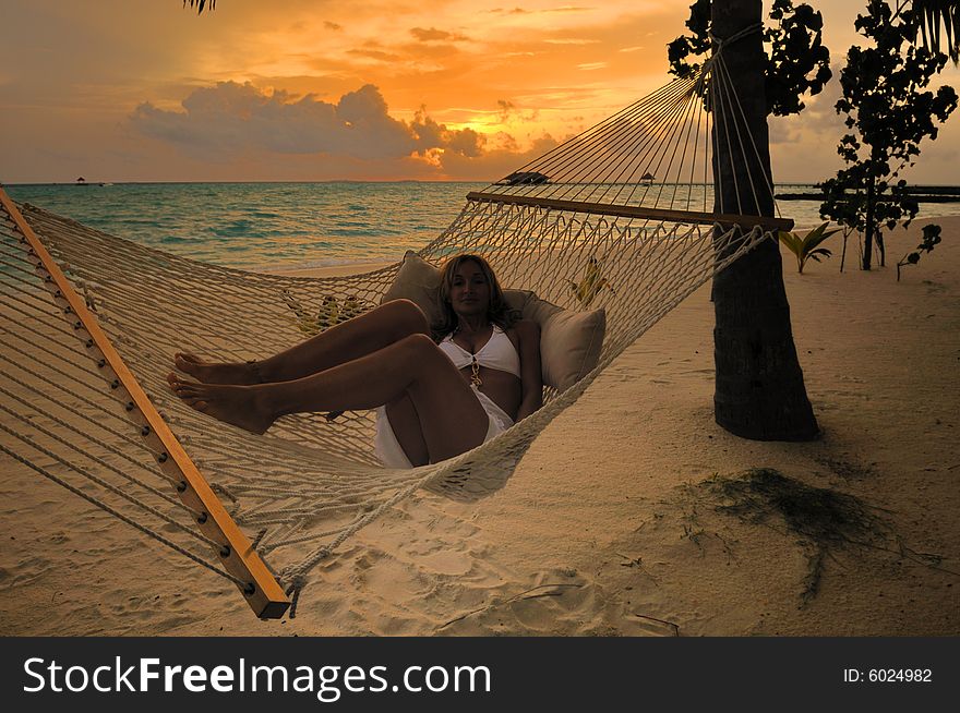 Beautiful woman lying in hammock near the ocean at Maldives