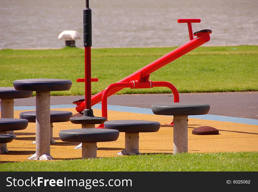 A children's playground at the waterfront with a red see-saw