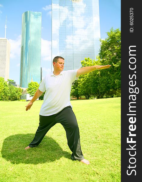Handsome caucasian man meditate outdoor in a park with downtown building in the background. concept for yoga or wellbeing. Handsome caucasian man meditate outdoor in a park with downtown building in the background. concept for yoga or wellbeing