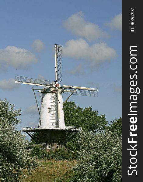A white windmill with a cloudy sky