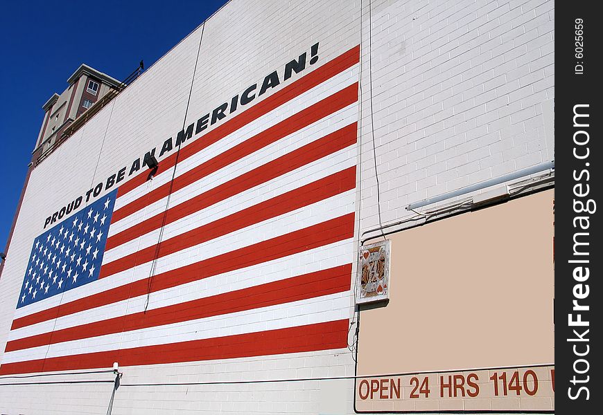 US flag on the brick wall with slogan proud to be american. US flag on the brick wall with slogan proud to be american