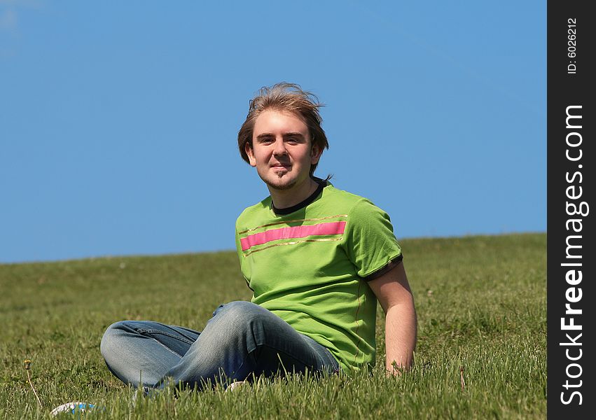 Happy young man sitting on the grass field