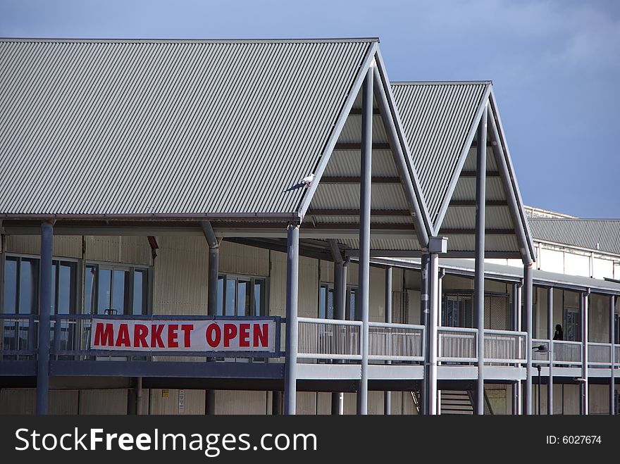 Red â€œMarket Openâ€ sign on the side of a large indoor market warehouse. Port Adelaide, South Australia. Possibly could be a metaphor for financal or free markets.