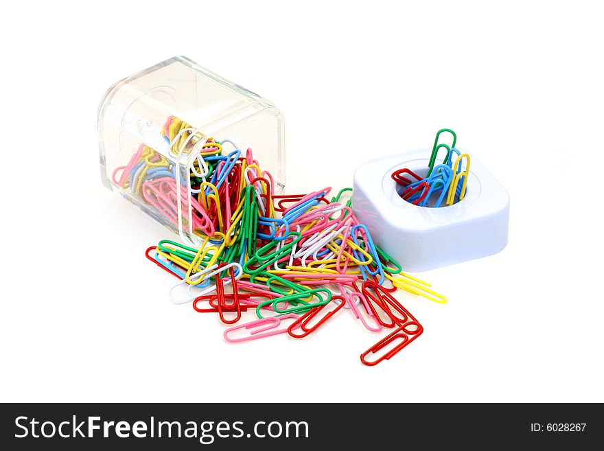 Colorful paper clips spilled from a paper clip holder.  Isolated on white with copy space.