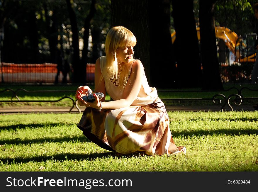 Girl squatting, holding a camera. Girl squatting, holding a camera