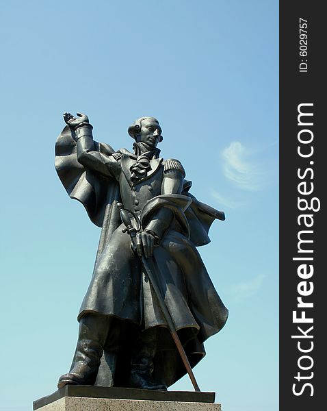 A gray and silver bronze statue of Major General Marquis De Lafayette against a blue sky with a small brush of clouds. A gray and silver bronze statue of Major General Marquis De Lafayette against a blue sky with a small brush of clouds