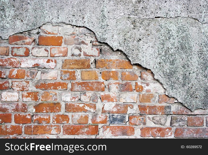 Old crumbling brick wall with cracked plaster