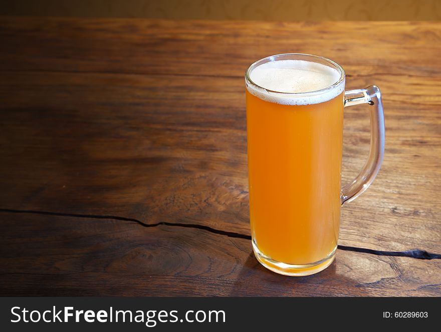 Mug of fresh beer on the wooden table. Mug of fresh beer on the wooden table