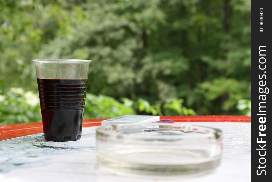 Plastic glass with wine on the table, background from leaf. Plastic glass with wine on the table, background from leaf