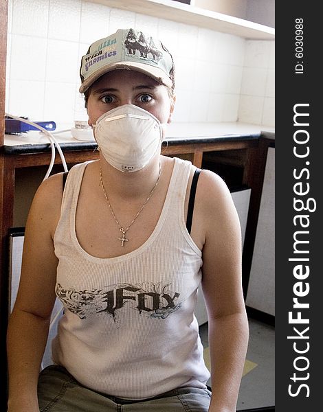 Woman renovating kitchen cupboard wearing a mask. Woman renovating kitchen cupboard wearing a mask