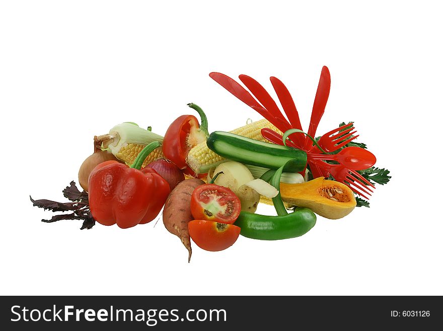 Composition from vegetables - carrots, pepper, a potato, fresh cucumbers and red plastic forks and spoons. Composition from vegetables - carrots, pepper, a potato, fresh cucumbers and red plastic forks and spoons