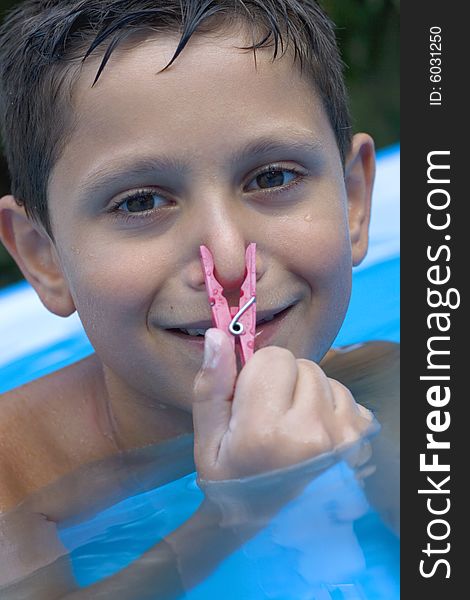 Young boy in pool with clothes peg