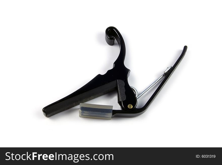 A photograph of a guitar capo against a white background