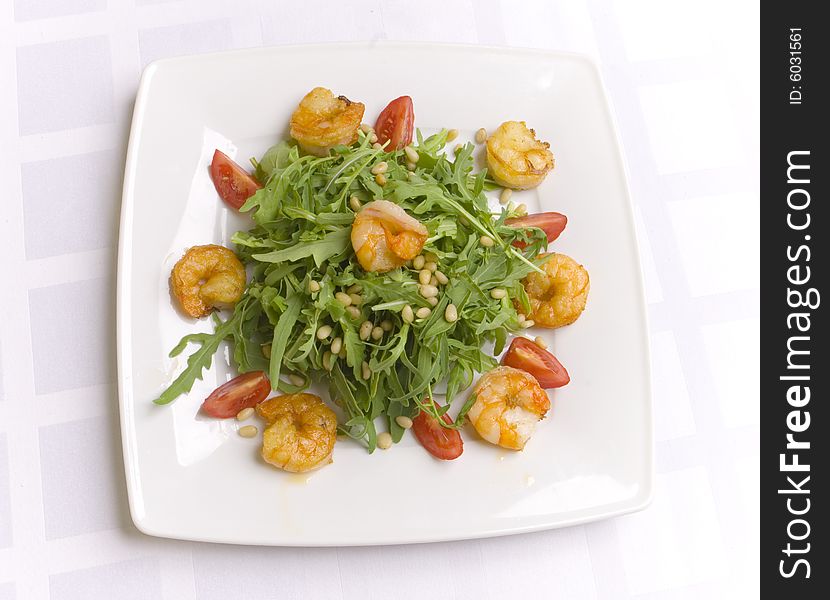 Salad with herbs, vegetables and shrimps on white plate