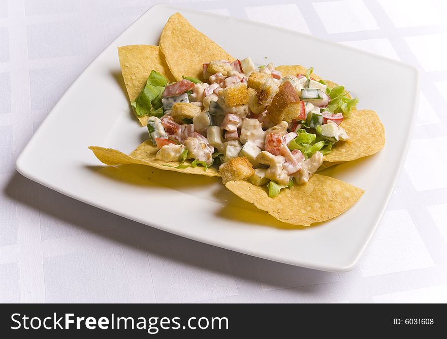 Salad decorated with nachos on white plate