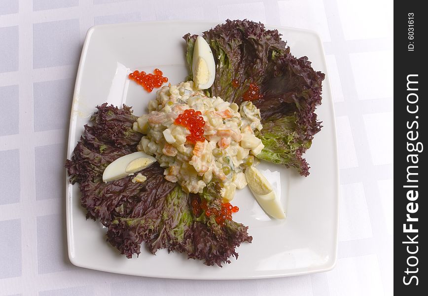 Salad decorated with leaves on white plate