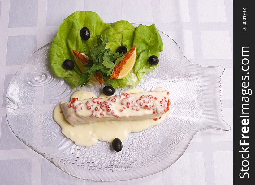 Salmon under creamy sauce decoratet with caviar and salad on plate. Salmon under creamy sauce decoratet with caviar and salad on plate