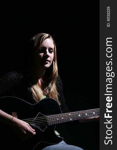 Woman playing guitar with dramatic lighting. Woman playing guitar with dramatic lighting