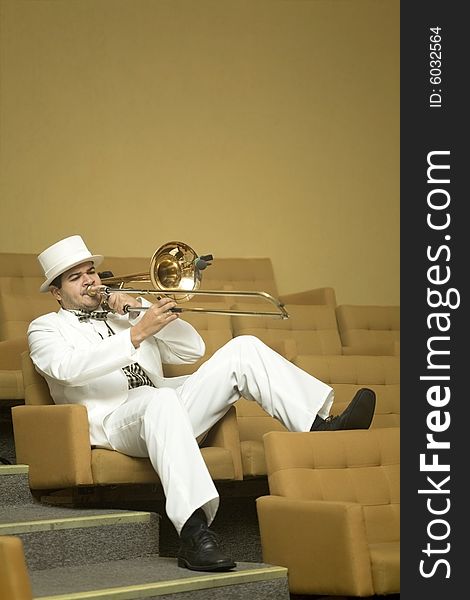 A trombonist in a white suit and yellow background. A trombonist in a white suit and yellow background.