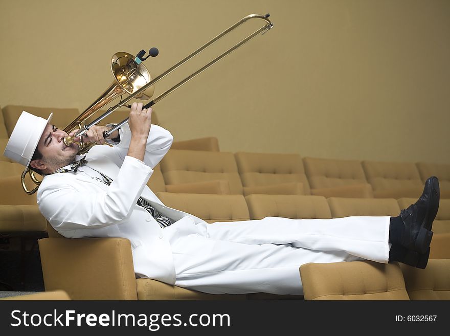 A trombonist in a white suit and yellow background. A trombonist in a white suit and yellow background.