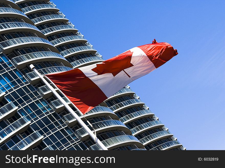 Canadian flag in a blue sky near big building