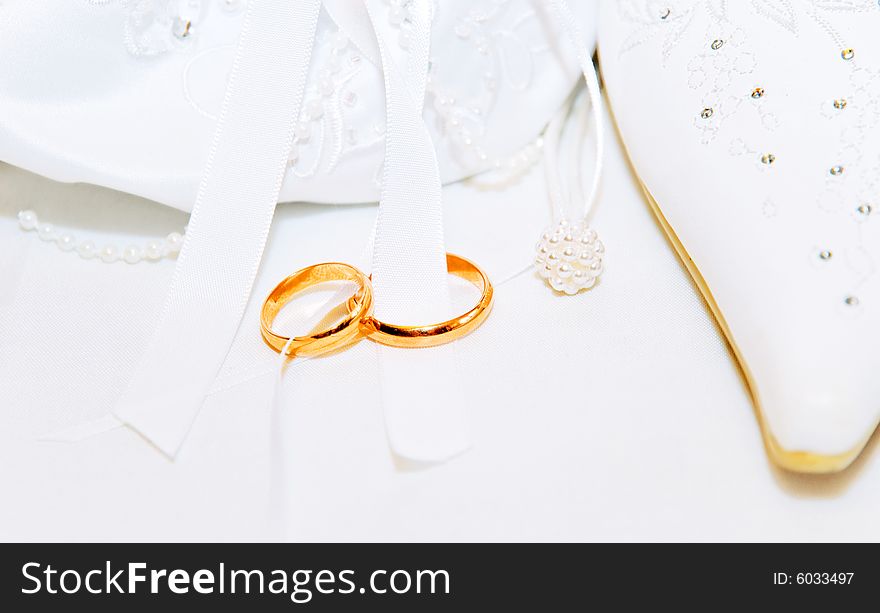 White wedding background with two gold rings, a show and a wedding bag. White wedding background with two gold rings, a show and a wedding bag