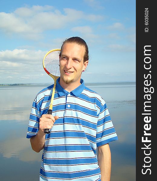 Young adult man with a racket for a badminton on the riverside. Rest on fresh air. Young adult man with a racket for a badminton on the riverside. Rest on fresh air.