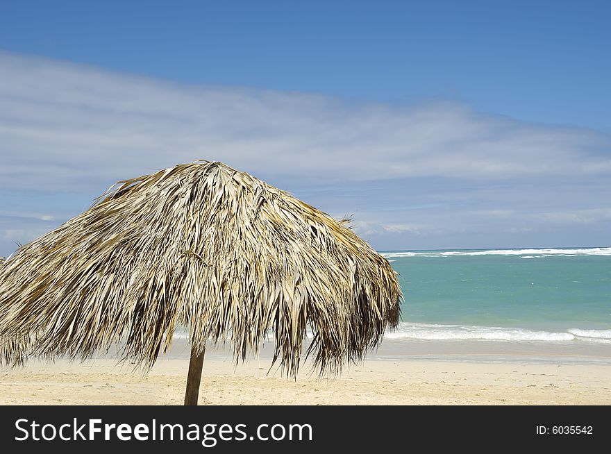 Parasol made out of palm leafs on beach.