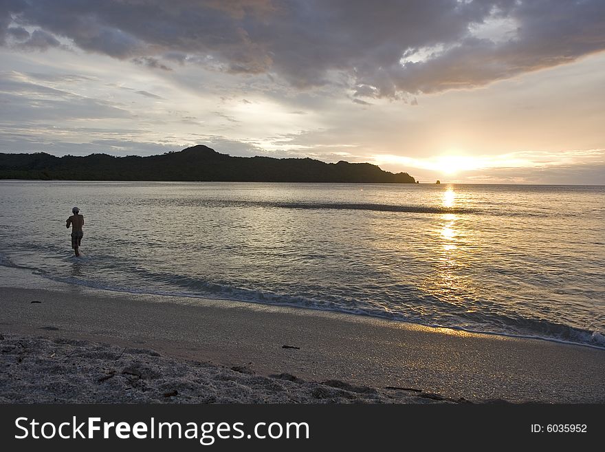 A man fishing on the beach as the sun sets. A man fishing on the beach as the sun sets