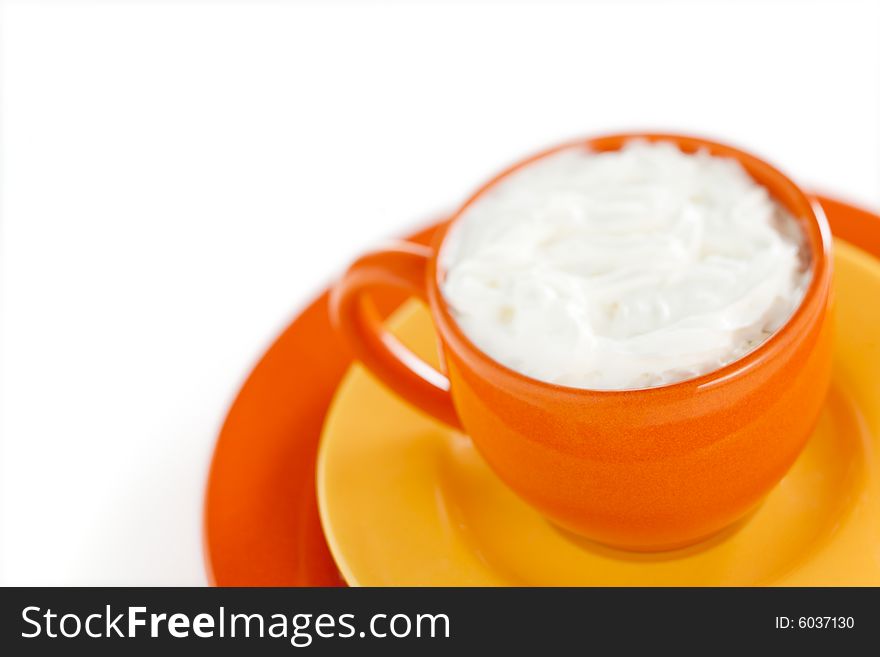 Orange coffee cup with yellow plate over white background