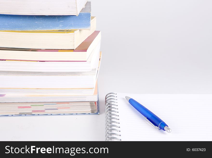 Stack of books, pen and notebook