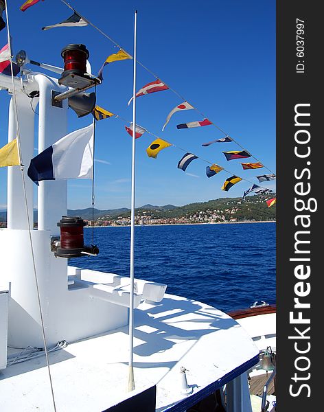 Coloured seafaring flags on a boat. These flags and their meaning costitutes the international code to communicate on sea. View of the city of Alassio in Liguria, Italy. Coloured seafaring flags on a boat. These flags and their meaning costitutes the international code to communicate on sea. View of the city of Alassio in Liguria, Italy.