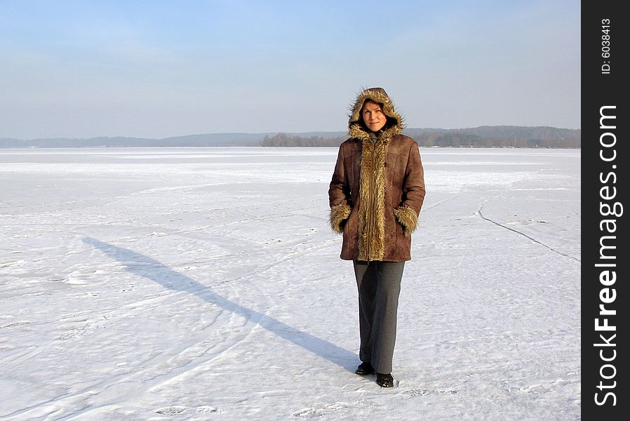 The girl standing on the vast frozen lake on a cold winter day in Lithuania. The girl standing on the vast frozen lake on a cold winter day in Lithuania.
