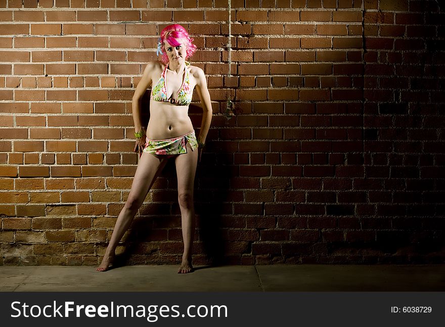 Pretty woman in a flowered bikini on a brick background. Pretty woman in a flowered bikini on a brick background