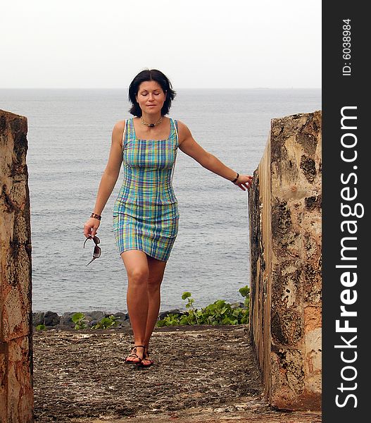 The girl walking on El Morro fort wall with Caribbean Sea in a background (San Juan, Puerto Rico). The girl walking on El Morro fort wall with Caribbean Sea in a background (San Juan, Puerto Rico).