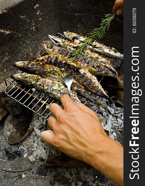 Man making grilled fishes with rosemary