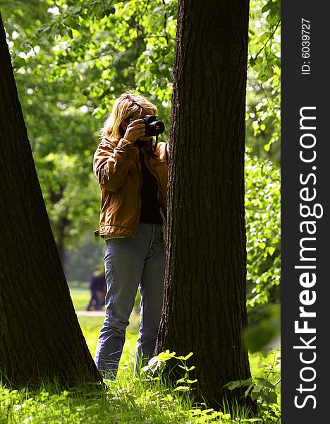 Woman photographer shooting a leaf on a tree